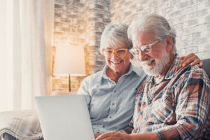 old people sitting on the sofa using laptop toget